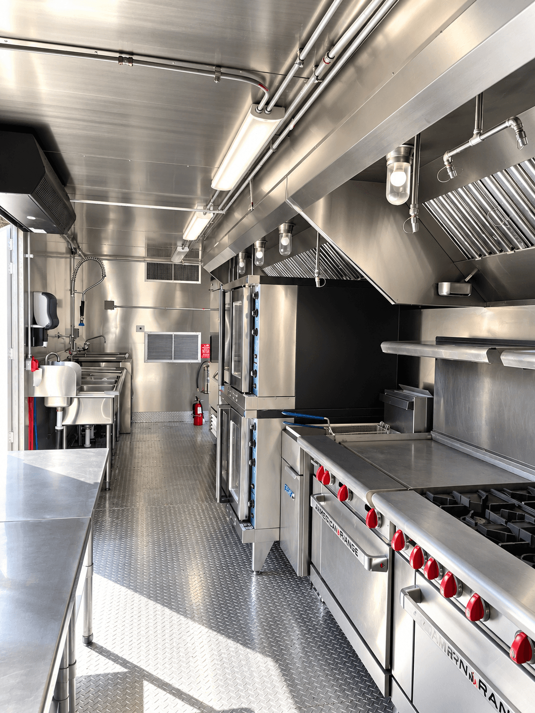 Commercial kitchen cooking line beneath an extraction hood with a central preparation table