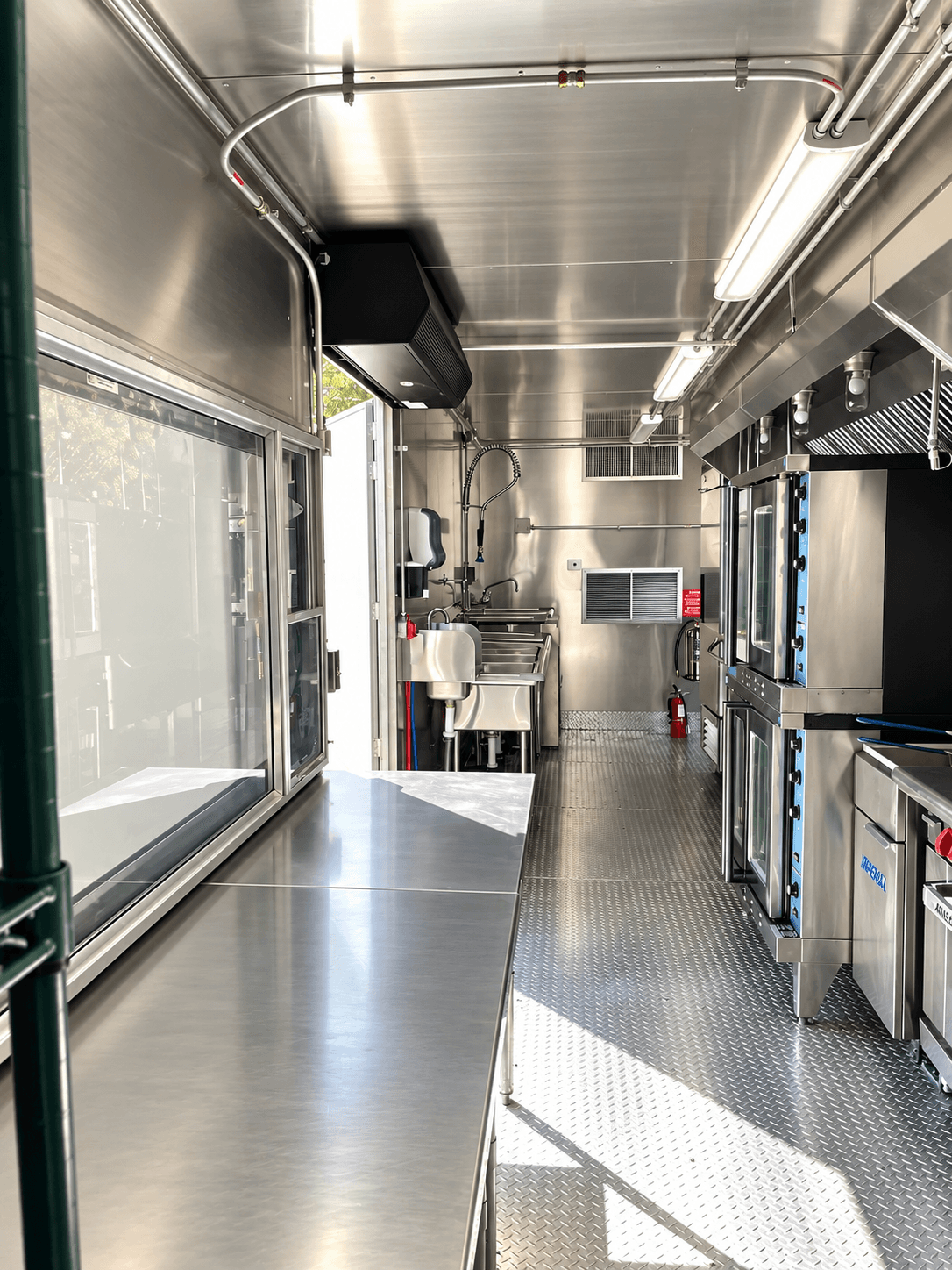 Stainless preparation counter, shelving and work aisle inside a kitchen trailer