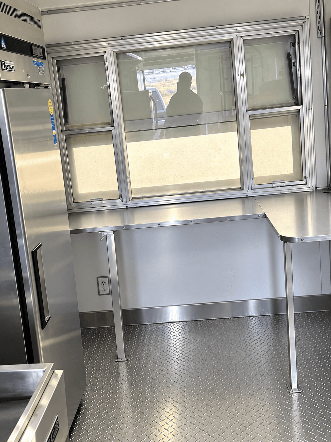 Stainless preparation counter beneath a kitchen trailer service window